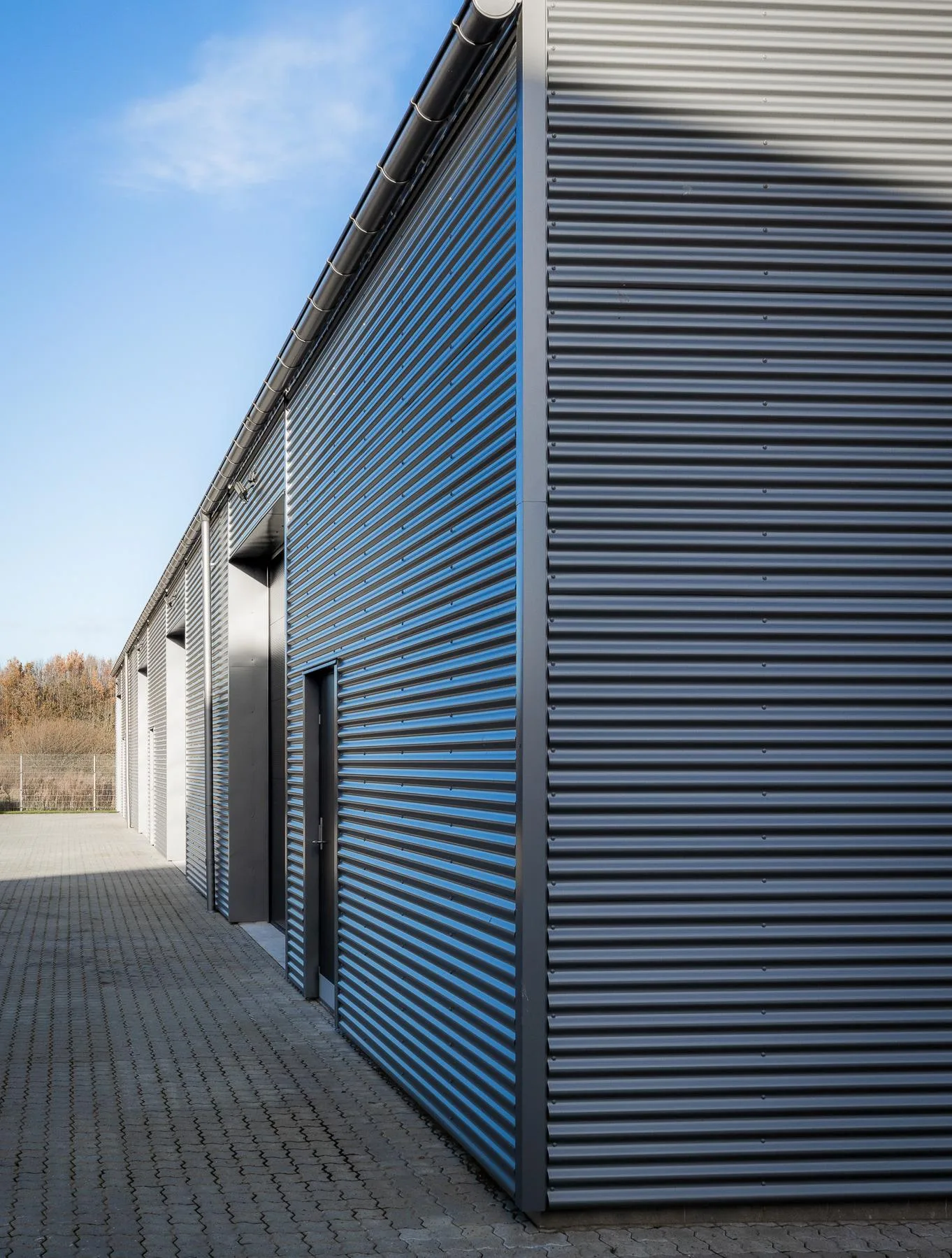 Haller i mørk stålbeklædning med porte i række på Marktoften i Galten
